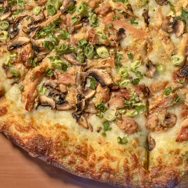 Aquarius pizza with a pesto base, garlic chicken, sliced mushrooms, and green onions